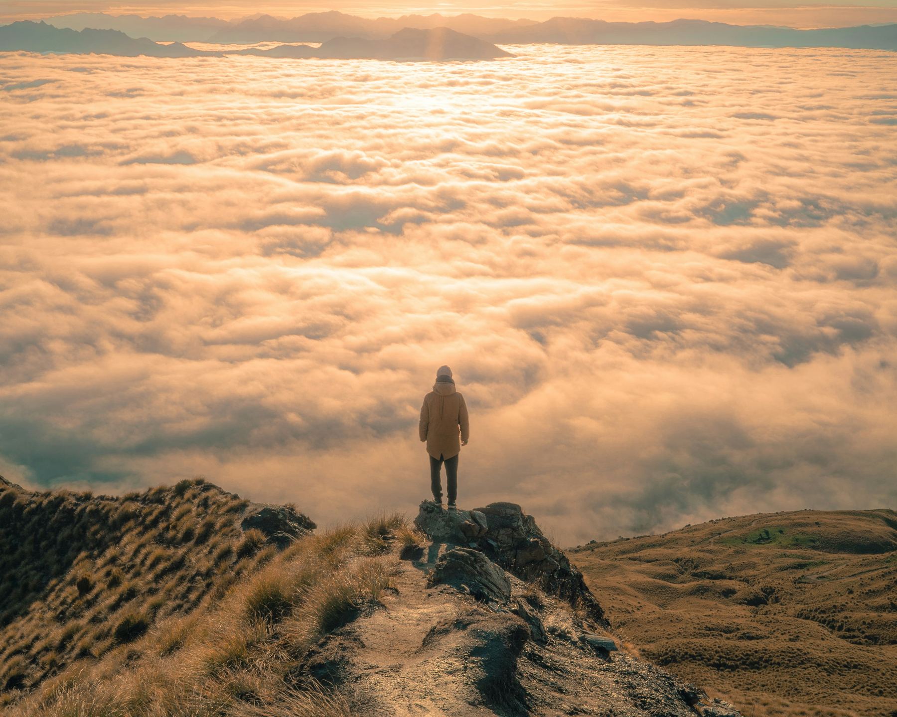 Wanderer steht über einem Wolkenmeer im goldenen Licht