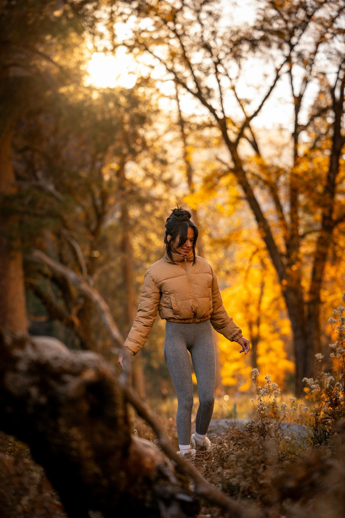 Person geht lächelnd durch einen herbstlichen Wald im goldenen Licht