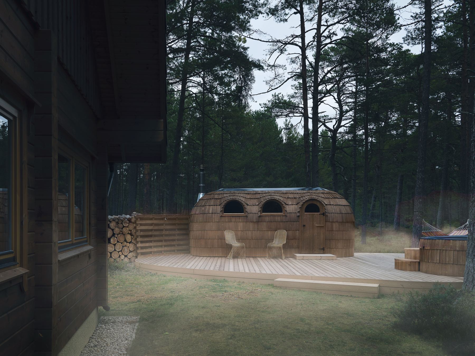 Rustikale Holzhütte mit Sauna im Wald, Terrasse mit zwei Stühlen